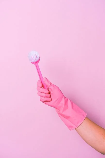 a-woman-in-a-green-shirt-and-black-gloves-vacuuming-a-gray-ottoman-5txz228u4eo